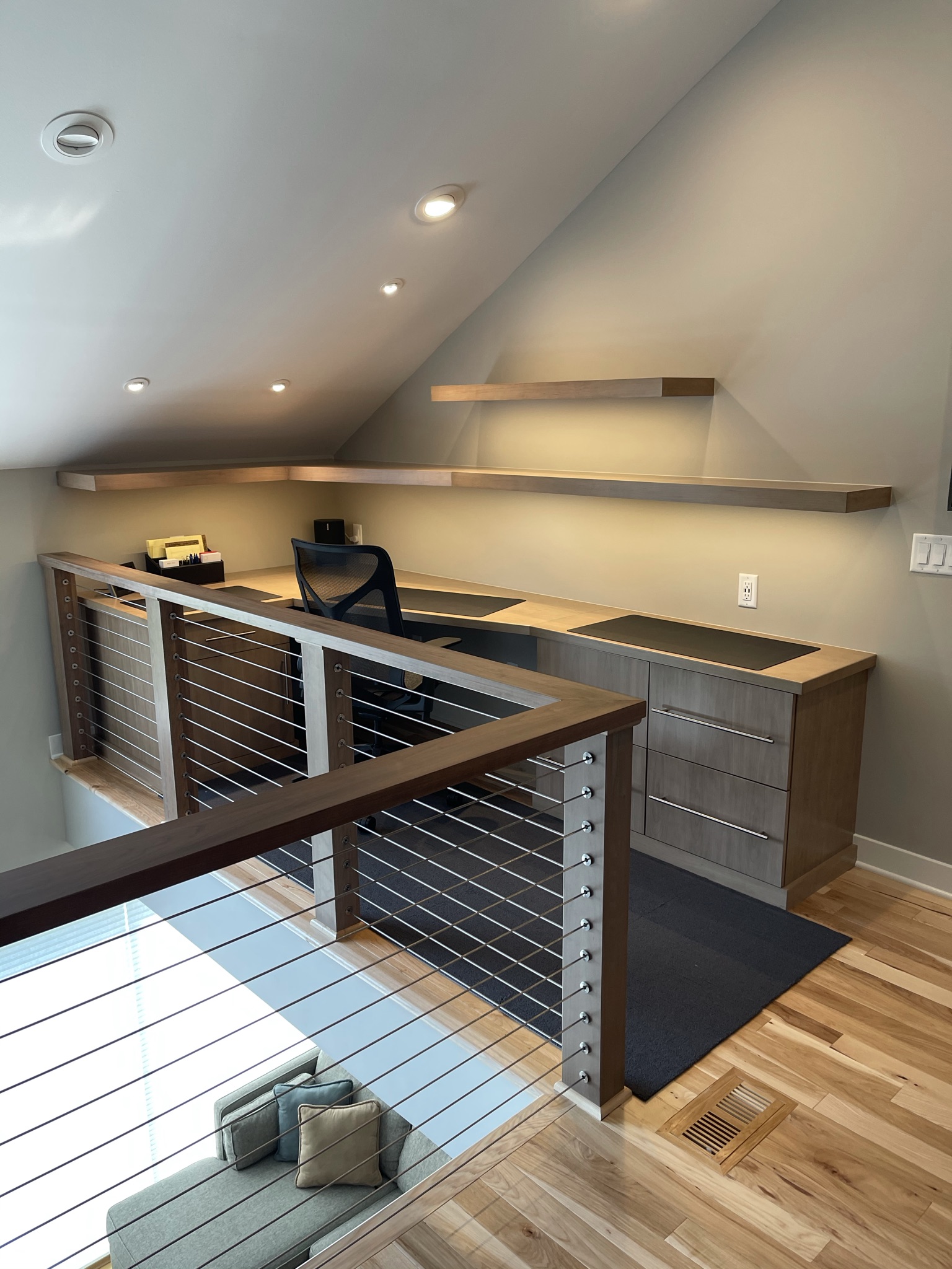 Office with custom desk, wood floors and railing.